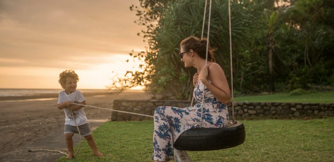femme sur une balancoire a pneu tiree par un garcon